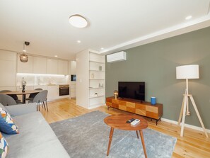 A modern living room with a sofa, coffee table, TV, and a dining area with chairs and a table. - Apartment  by Interhome (Porto)