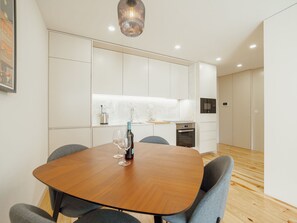 Eine moderne Küche mit wei ßen Schränken, einem Holztisch und grauen Stühlen.