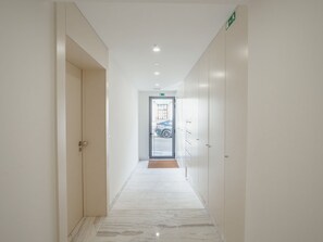 A corridor with a door on the left, a door on the right, and a view of the outside through a glass door at the end. - Apartment  by Interhome (Porto)