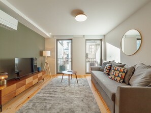 A modern living room with a television, a lamp, a sofa, and a round mirror. - Apartment  by Interhome (Porto)