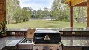 A kitchen with a Broil King grill, a stone countertop, and a view of a grassy yard. - Shoals Area Oasis w/ Boat Dock & Outdoor Kitchen (Florence)