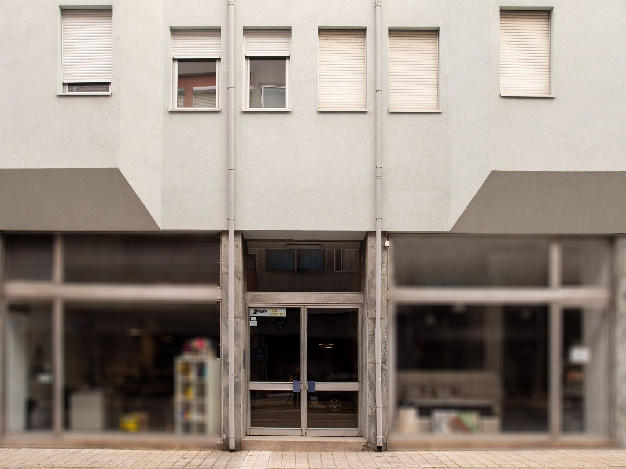 A building facade with a central entrance, multiple windows, and a visible sign for a data systems company.