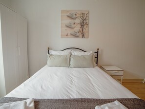 Une chambre à coucher comprenant un lit, une table de chevet, une œuvre d’art accrochée au mur et une armoire.