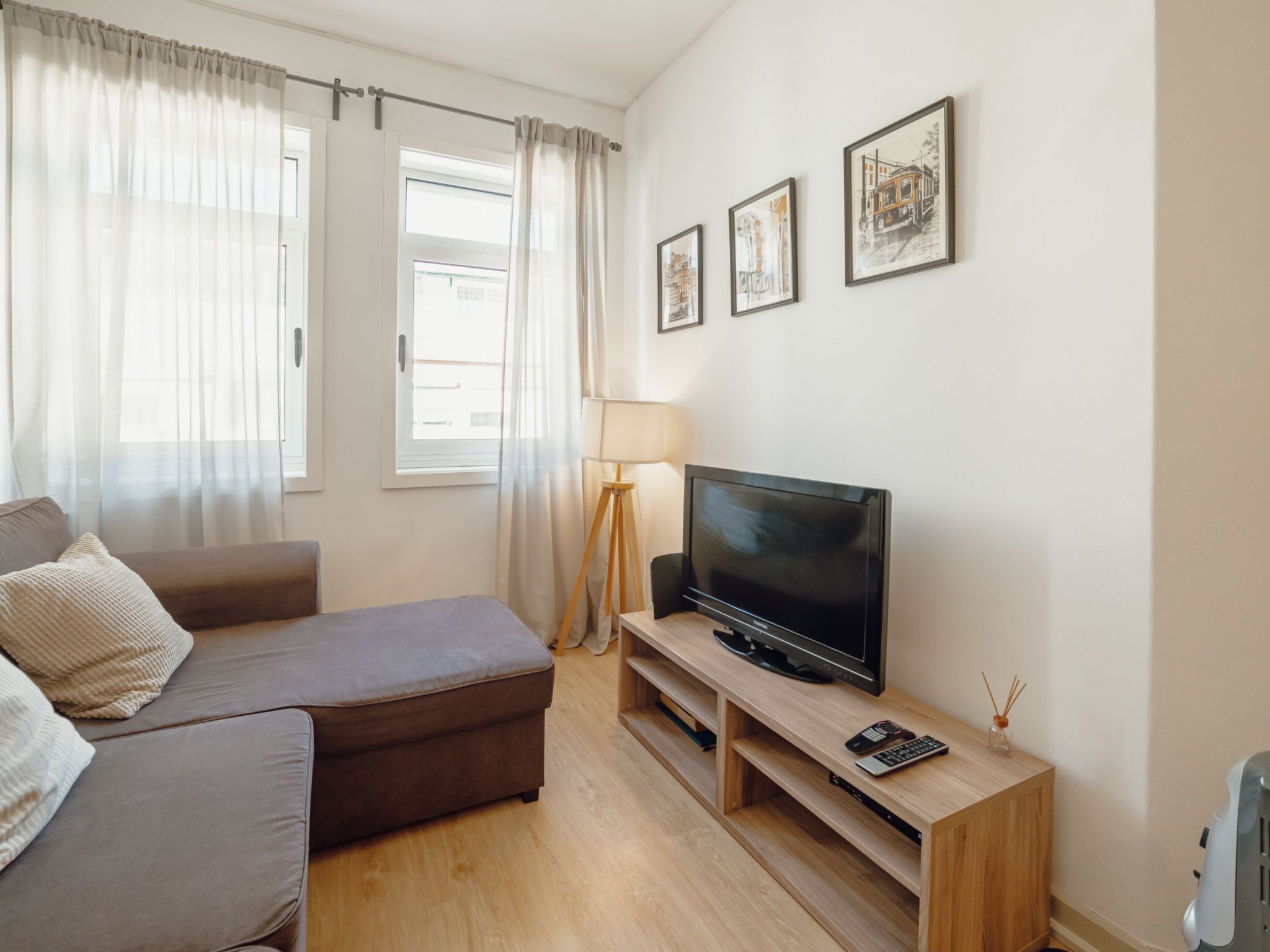 Una sala moderna con un sofá, un televisor de pantalla plana y una lámpara.