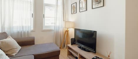 A modern living room with a sofa, a flat-screen TV, and a lamp.