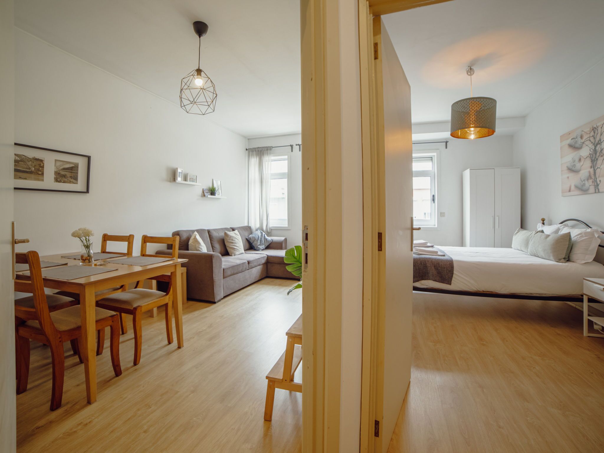 A modern interior with a dining area, a sofa, a bed, and a hallway.