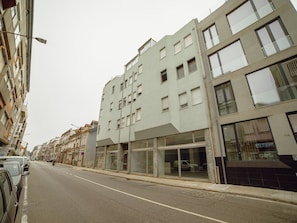 A multi-story building with a modern facade, large windows, and a ground-level commercial space. - Apartment  by Interhome (Porto)