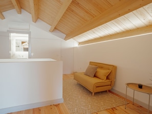 A modern, minimalist room with a wooden ceiling, a sofa, a small table, and a patterned rug. - Apartment  by Interhome (Porto)
