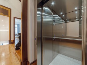 A modern elevator with a metallic finish and a glass door. - Apartment  by Interhome (Porto)