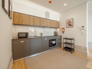 A modern kitchen with grey cabinets, a microwave, a coffee maker, and a small shelf. - Apartment  by Interhome (Porto)