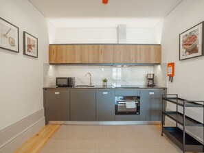 A modern kitchen with grey cabinets, a microwave, a coffee maker, and a small oven. - Apartment  by Interhome (Porto)