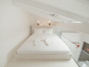 Une chambre à coucher minimaliste avec un lit simple, du linge de lit blanc et deux lampes de chevet.