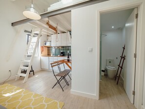 Un appartement moderne de style « loft », comprenant une cuisine, un coin repas et une salle de bain ouverte.