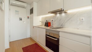 Una cocina moderna con gabinetes blancos, un extractor de acero inoxidable, un tostador rojo y una alfombra roja en el suelo.