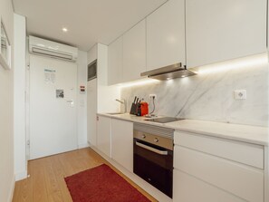 Eine moderne Küche mit weißen Schränken, einer Edelstahl-Dunstabzugshaube, einem roten Toaster und einem roten Teppichboden.