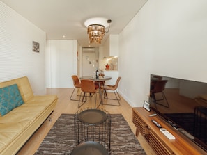 A modern living room with a sofa, dining table, chairs, a TV, and a chandelier. - Apartment  by Interhome (Porto)