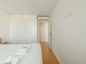 A bedroom with a bed, a wardrobe, and an air conditioning unit. - Apartment  by Interhome (Porto)