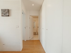 Un couloir doté d’un plancher en bois, de murs blancs et d’une porte donnant sur une salle de bain.