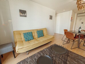 Un salon moderne comprenant un canapé, deux fauteuils, une table à manger et un tapis à motifs.