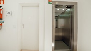 Un ascensor con interior metálico y una puerta blanca con un cartelito encima.