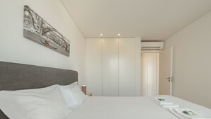 Habitación de hotel con una cama grande, un armario, un equipo de aire acondicionado y un cuadro en la pared.
