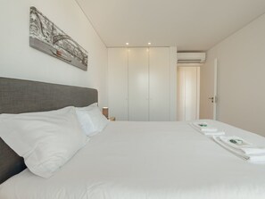 Ein Hotelzimmer mit einem großen Bett, einem Kleiderschrank, einer Klimaanlage und einem gerahmten Bild an der Wand.