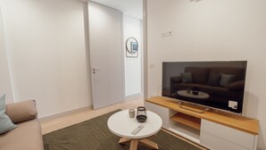 En moderne stue med et fladskærms-tv, et rundt sofabord og en sofa.