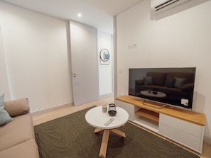 Ein modernes Wohnzimmer mit Flachbildfernseher, einem runden Couchtisch und einer Couch.
