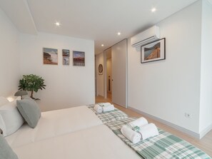 A modern bedroom with a bed, a plant, and a wall-mounted air conditioner. - Apartment  by Interhome (Porto)