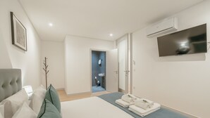 Et moderne hotelværelse med en seng, et fladskærms-tv og et badeværelse, der kan ses gennem en åben dør.