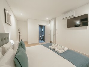 Ein modernes Hotelzimmer mit einem Bett, einem Flachbildfernseher und einem durchgegangene Tür sichtbar liegenden Badezimmer.
