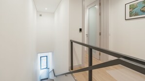 Et moderne interiør med en trappe, der fører til en repos, en dør og et billede i ramme på væggen.