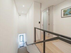 Ein modernes Interieur mit einer Treppe, die zu einer Zwischenebene führt, einer Tür und einem gerahmten Bild an der Wand.