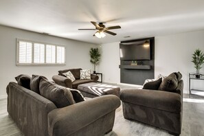 A living room with a sofa set, a ceiling fan, a flat-screen TV, and a fireplace. - Mountain-View Haven: Home Near Fort Bliss (El Paso)