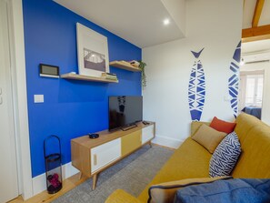 A living room with a blue wall, a television, a wooden cabinet, and a yellow sofa. - DOWNTOWN PRIME with TERRACE by VACATIONY by Interhome (Porto)