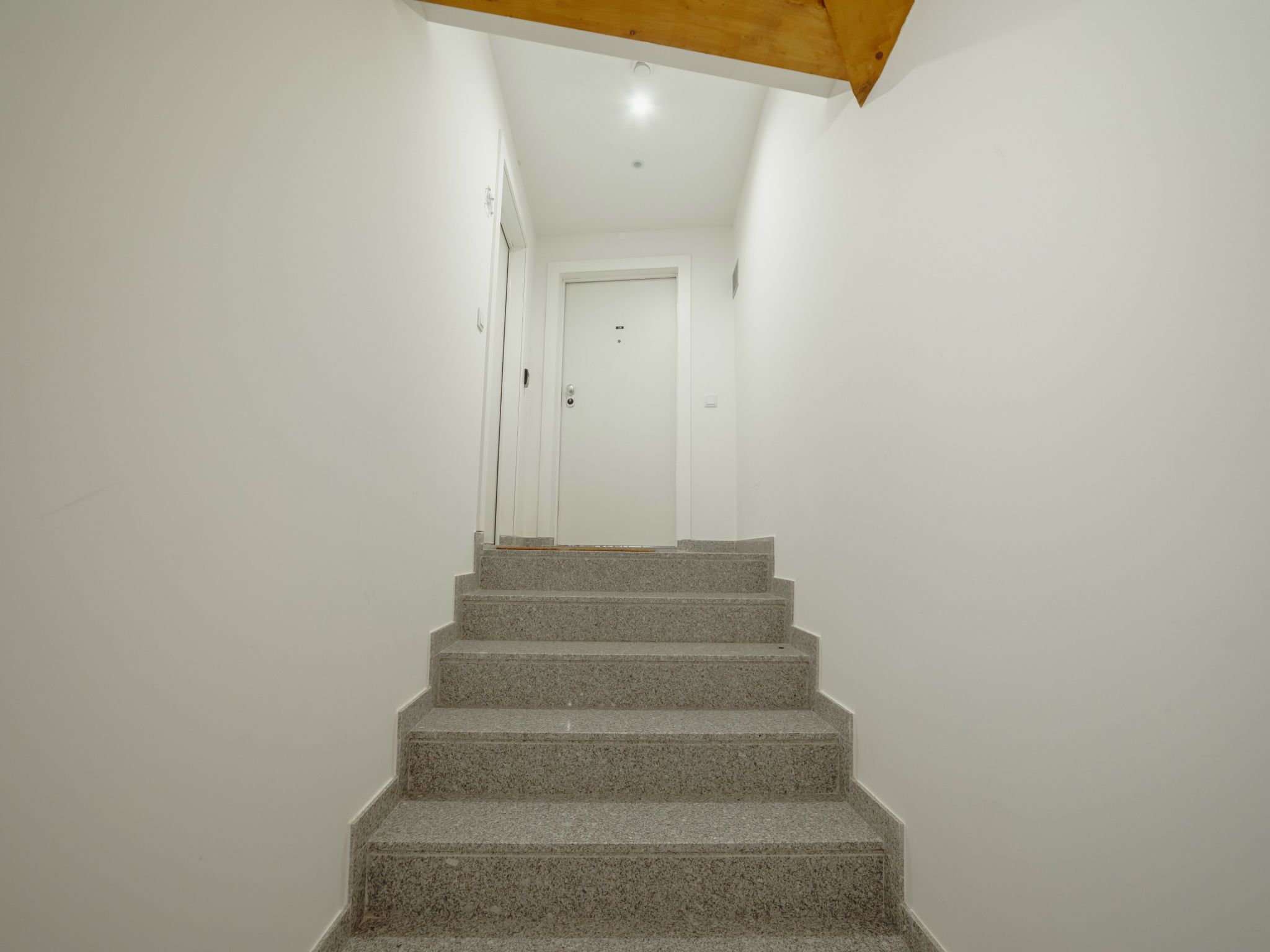 A staircase leading to a white door with a ceiling light.
