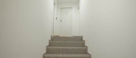 A staircase leading to a white door with a ceiling light.
