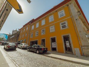 A street with a yellow building, cobblestone pavement, and parked cars. - DOWNTOWN PRIME with TERRACE by VACATIONY by Interhome (Porto)