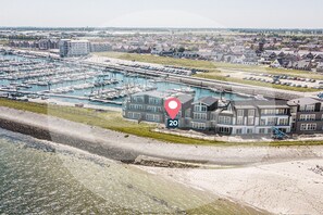 Eine Vogelperspektive auf einen Yachthafen mit Booten, ein großes Gebäude mit einem roten Positionsmarker und umliegende Wohngebiete.