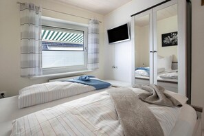 Ein Schlafzimmer mit zwei Betten, einem Fernseher und einer Schiebetür zu einem Badezimmer.