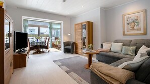 Een moderne woonkamer met een bank, televisie, eettafel en stoelen.
