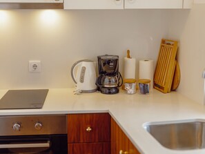 A kitchen with a coffee maker, kettle, and paper towels on the counter. - Apartment  by Interhome (Porto)