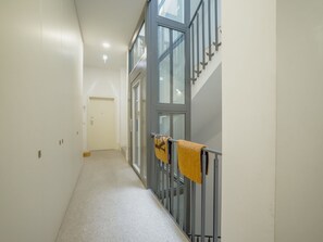 A corridor with a carpeted floor, a metal railing with a towel, and a door at the end. - Apartment  by Interhome (Porto)