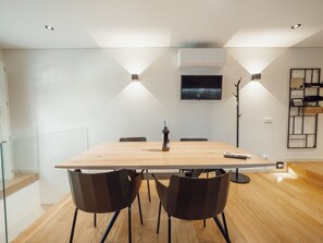 Ein moderner Essbereich mit einem Holztisch, vier Stühlen und einer Weinflasche.