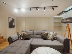 Un salon moderne avec un canapé d’angle, une table basse en marbre et un lampadaire.