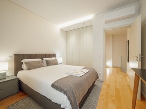 A modern bedroom with a large bed, bedside tables, a wardrobe, and a built-in air conditioning unit. - Apartment  by Interhome (Porto)