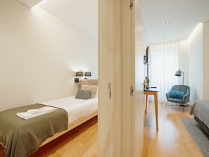 Ein modernes Schlafzimmer mit einem Einzelbett, Nachttischlampen, einem kleinen Tisch und einem Stuhl.