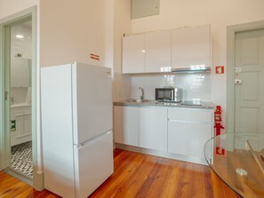 Une cuisine compacte avec des meubles blancs, un four à micro-ondes encastré et un évier en acier inoxydable.
