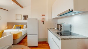 Una habitación de hotel compacta con cama, una kitchenette pequeña y un área de comedor.