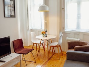 A modern living space with a dining area, a sofa, a TV, and a lamp. - Apartment  by Interhome (Porto)